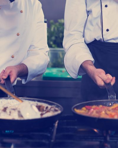 Professional team cooks and chefs preparing meals at busy hotel or restaurant  kitchen